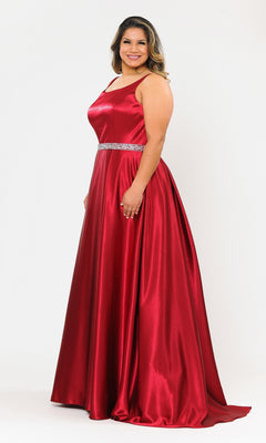 A woman wearing the Sleeveless Plus-Size Long Belted Prom Dress W1010 in shiny red with a jeweled waistband stands smiling against a plain white background.
