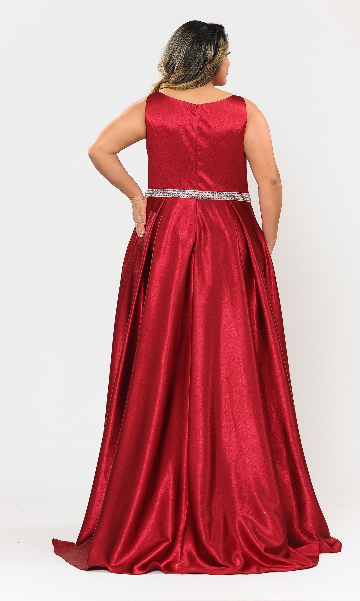 A woman stands facing away in the Sleeveless Plus-Size Long Belted Prom Dress W1010, featuring a red satin finish, silver beaded belt, and pleated floor-length skirt against a white background.
