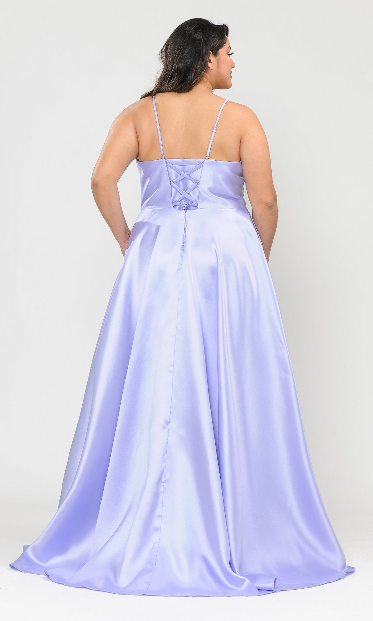 A woman wears the Plus-Size Long Corset Prom Dress with Pockets W1070, a floor-length lavender satin gown with thin straps and lace-up back, standing against a plain white background.
