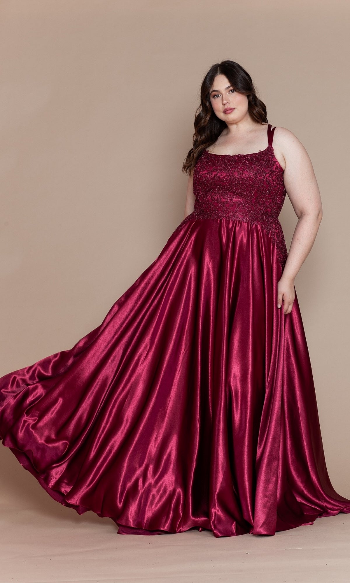 A woman models the Lace-Bodice Plus-Size Long A-Line Prom Dress W1094, featuring a flowing deep red skirt and embroidered lace bodice, as she stands against a plain beige background.