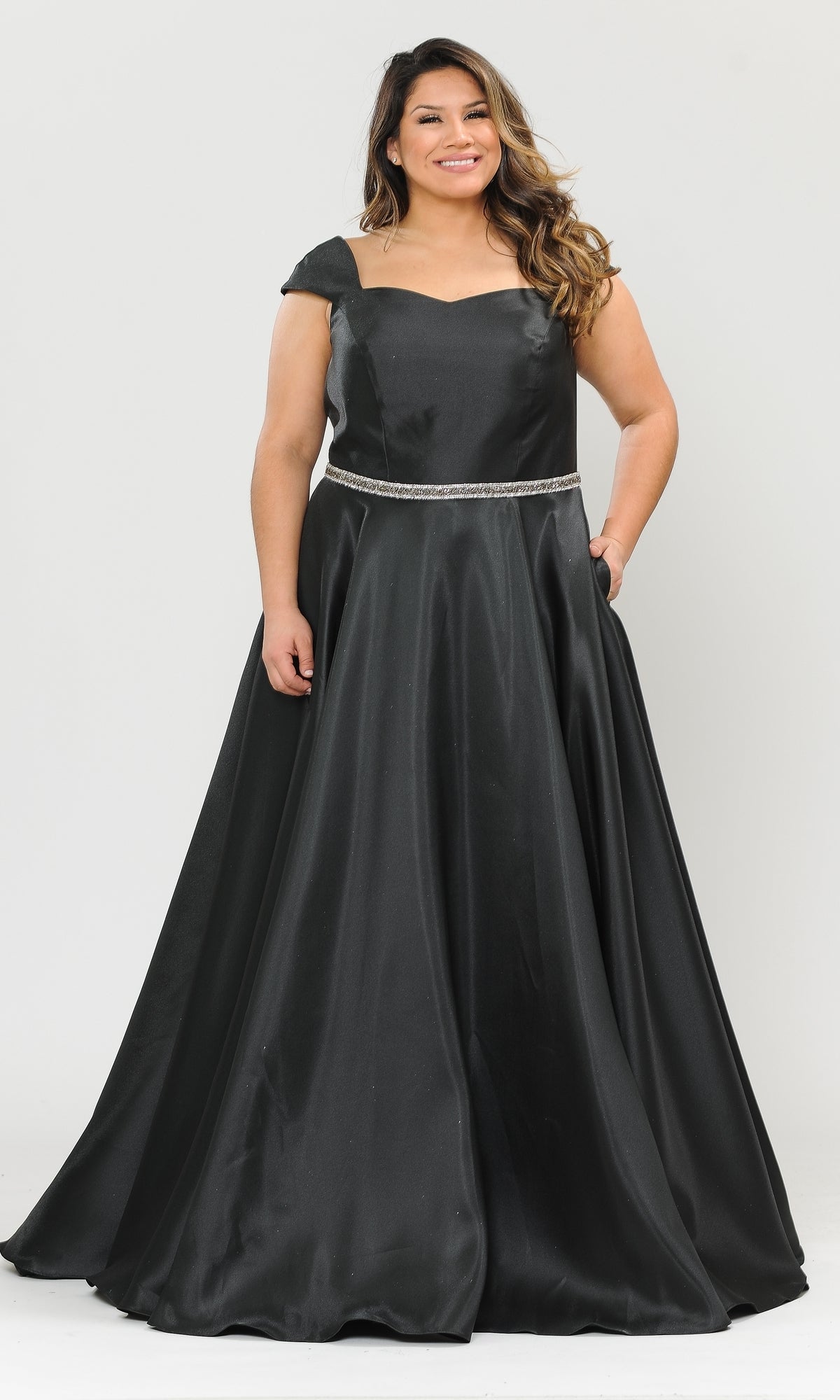 A woman wears the Plus-Size Cap-Sleeve Long Prom Dress W1104, a black formal gown featuring cap sleeves, a fitted bodice, jeweled belt, side pockets, and an A-line silhouette, standing against a plain white background.
