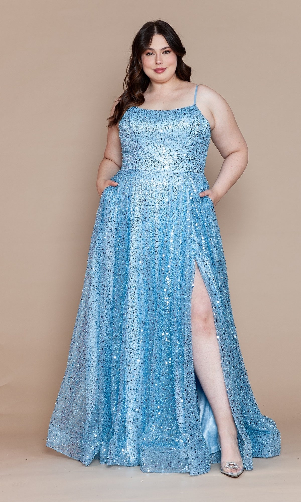 A woman in the blue Corset-Back Plus-Size Long Sequin Prom Dress W1142, featuring a thigh-high slit, poses against a plain beige background.