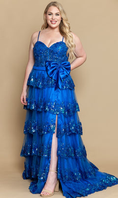 A woman models the PolyUSA W1162 plus-size tiered prom dress, featuring bright blue sequins, spaghetti straps, a large waist bow, ruffled layers, and a front slit, set against a beige background.
