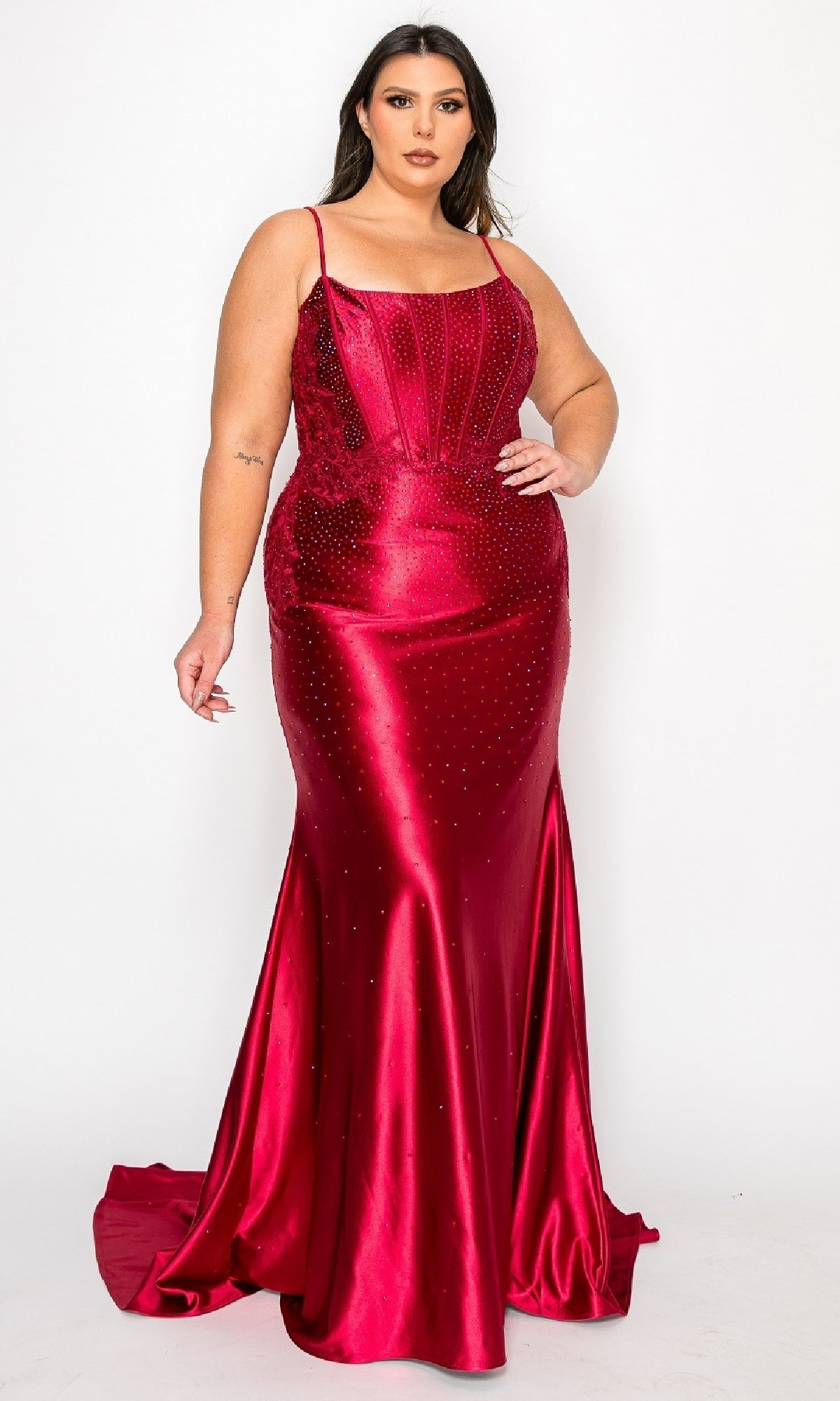 A woman models the Plus-Size Tight Beaded Prom Dress: PolyUSA W1164—a fitted, floor-length red satin gown with thin straps, bead accents, and a flared hem—standing against a plain white background.