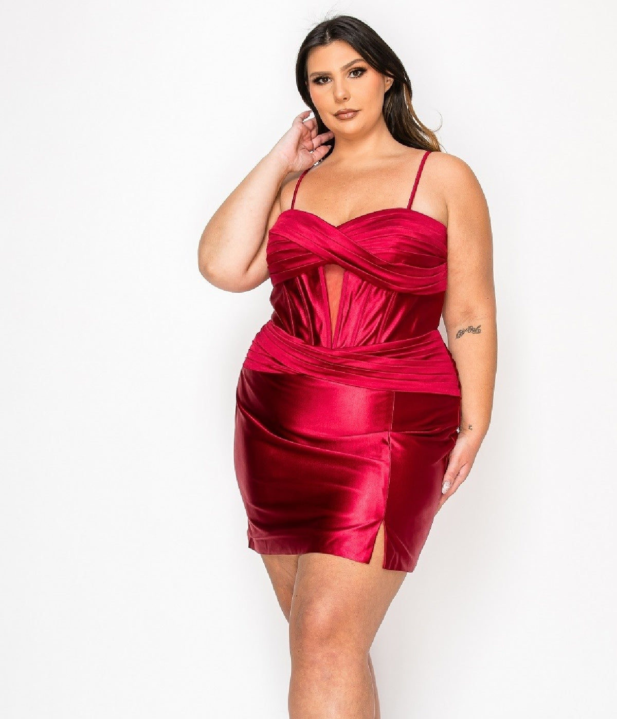 A woman wears the Plus-Size Mini Wedding Guest Dress: Poly USA W1174 in Red Wine, featuring thin straps, a front cutout, and a thigh-high slit, as she poses against a white background.