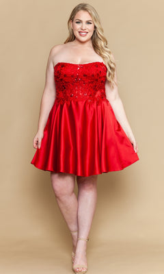 A woman poses against a beige background in the Poly USA W1220—a plus-size strapless party dress with a sequined corset-style bodice, A-line skirt with pockets, and nude high heels.
