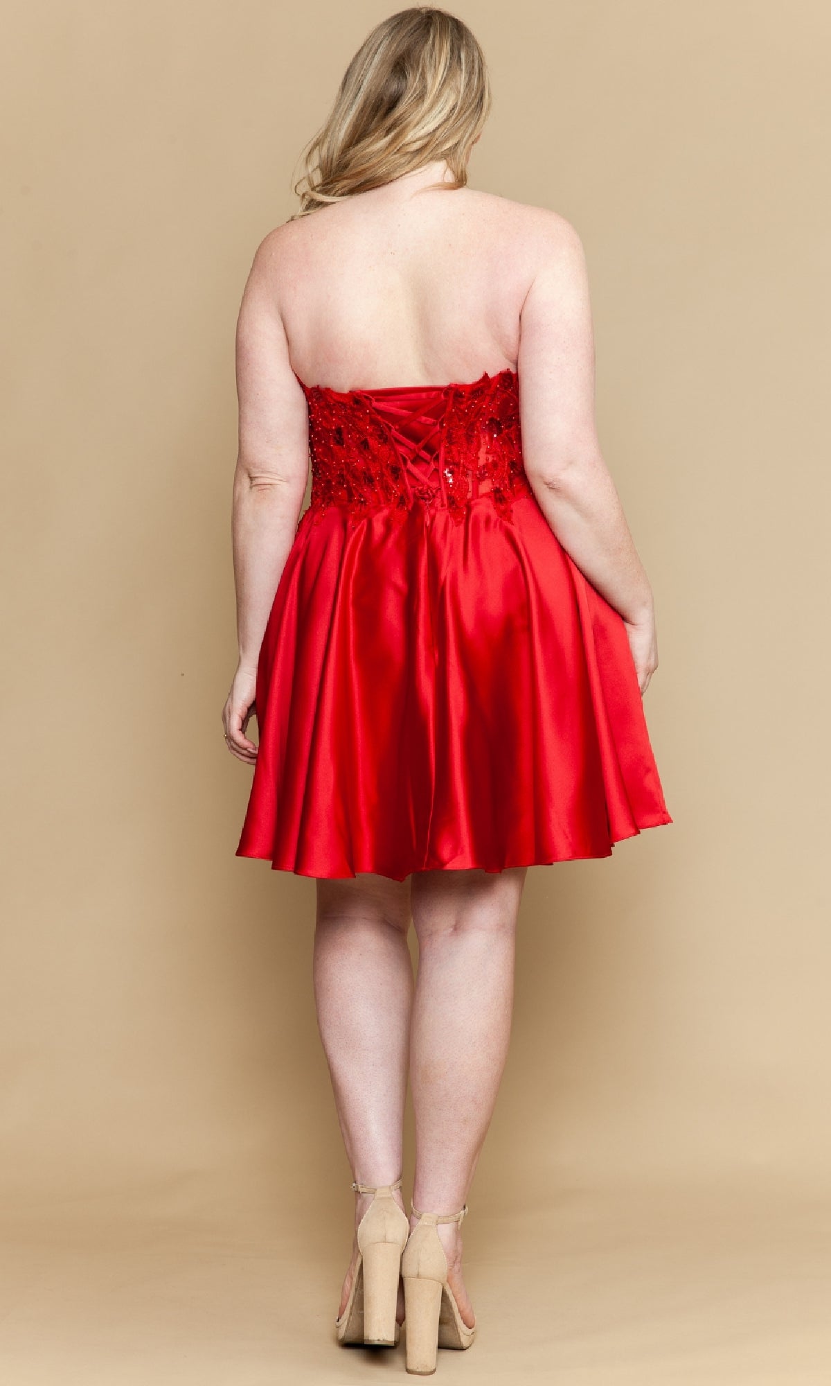 Woman wearing a red strapless dress on a beige background