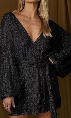 Woman wearing the Short Sequin Party Wrap Dress with Sleeves, featuring a v-neckline and belted waist, posing against a brown background.
