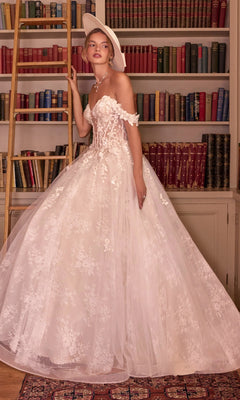 A woman wearing the Long French White Wedding Dress: Andrea & Leo WL093, an off-the-shoulder, floor-length French lace gown paired with a wide-brim hat, standing in front of a bookshelf.