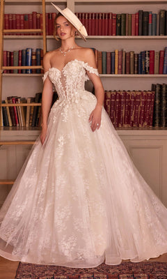 Off-the-shoulder Long French White Wedding Dress: Andrea & Leo WL093 with a lace bodice, floral appliqués, and a full, layered skirt, worn with a wide-brim hat.