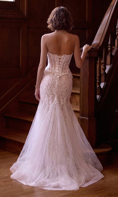 Wearing the Andrea & Leo WL091 Long Wedding Dress, a person stands on a wooden staircase facing away, showcasing the strapless beaded lace corset and tulle gown with intricate back detailing.