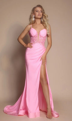 A woman wears the Portia and Scarlett XO039 long pink prom dress, featuring a floral embroidered corset, deep V-neckline, high slit, and flowing satin skirt, while standing against a plain beige background.