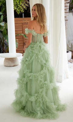 A woman stands indoors, facing slightly away from the camera, wearing the Sheer-Waist Off-Shoulder Long Prom Ball Gown Y1472 in light green with ruffled tulle.