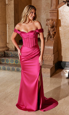 A woman stands indoors in the Nox Anabel Y1547 Off-Shoulder Long Prom Dress, a bright pink gown with a fitted bodice and thigh-high slit—perfect for formal evenings.