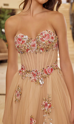 A woman wears the Nox Anabel Y1803 long prom dress, a strapless nude tulle gown with embroidered pink and red floral details and sparkling sequin accents.