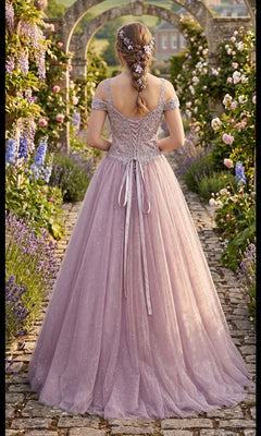 Wearing the Long Formal Dress: Chicas YG5012—a lavender ballgown with a lace-embroidered bodice—a woman, adorned with floral hair accessories, stands facing away on a flower-lined stone path in a garden filled with archways and blooming plants.