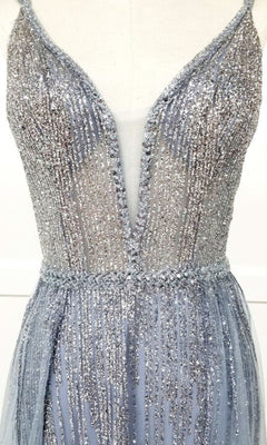 A close-up of the Sheer-Waist Long Sequin Prom Dress (Chicas YG5021), a sleeveless silver evening gown with a deep V neckline, sheer mesh panel, and glittering sequin print, displayed on a dress form.