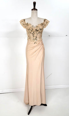 The Sequin-Bodice Long Prom Dress (Chicas YG5027) is a beige, floor-length gown with off-the-shoulder short sleeves and a sequin corset bodice decorated with gold floral embellishments, shown on a dress form.