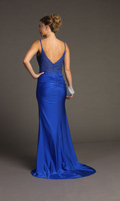 A woman in the Lace-Bodice Slinky Long Prom Dress (Chicas YG5033), a royal blue floor-length gown with embroidered lace and delicate back detail, holds a silver clutch against a plain gray background.