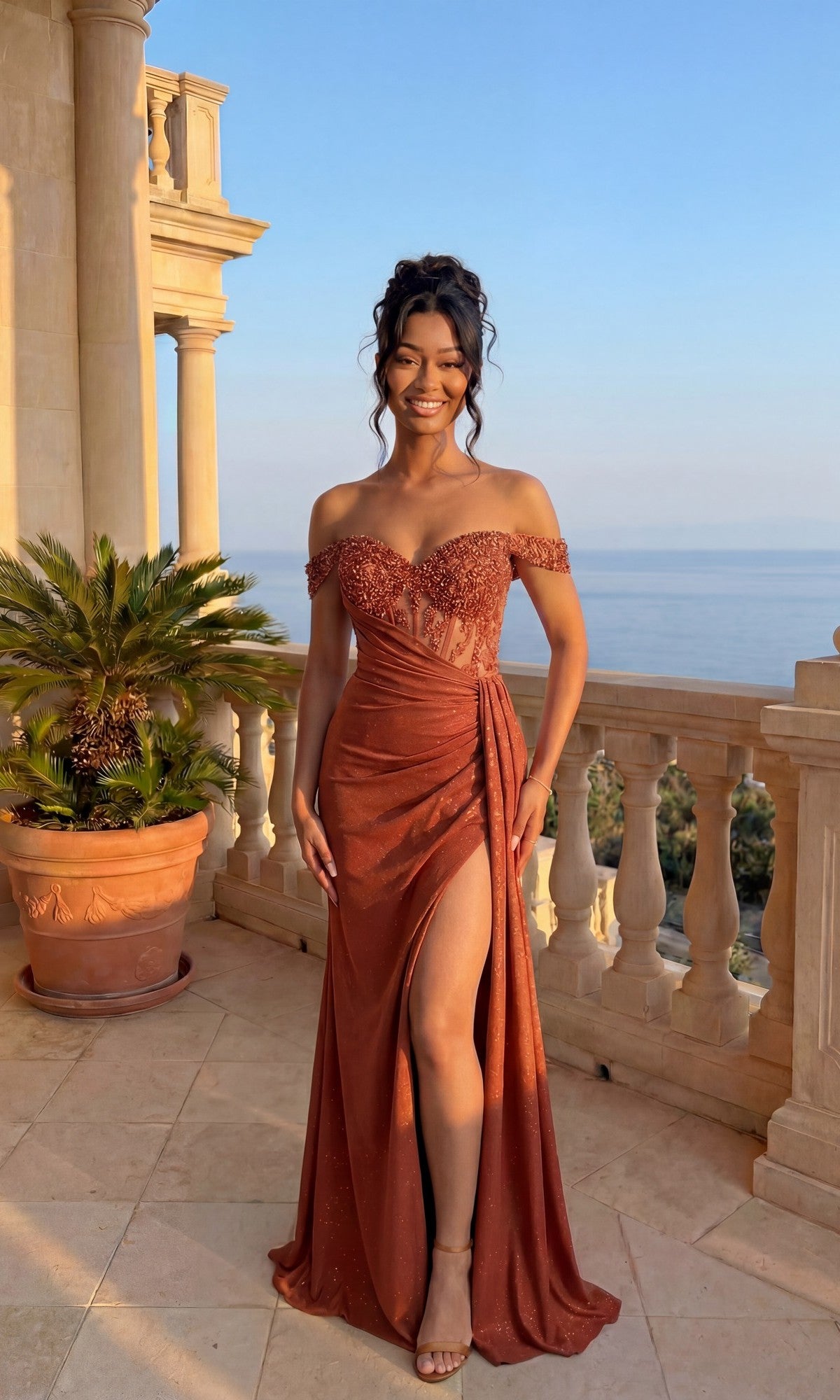 A woman in the Chicas YG5037 Long Formal Dress in burnt orange, featuring an off-shoulder design and thigh-high slit, stands on a balcony with ocean views framed by palm trees and classical columns.
