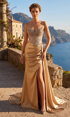 A woman stands on a stone terrace overlooking a coastal landscape, wearing the Chicas YG5041 Long Prom Dress in gold—designed with a strapless silhouette, sheer beaded bodice, and thigh-high slit.