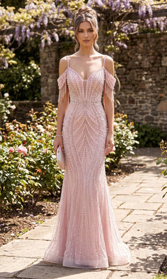 A woman in the Long Prom Dress: Chicas YG5042 in blush, a pearl-embellished off-the-shoulder gown, stands on a garden path holding a clutch, with flowers and a stone wall in the background.