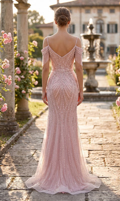 A woman wearing the Long Prom Dress: Chicas YG5042, adorned with pearls, stands on a stone path in a rose-filled garden, with stone columns and a fountain in the background.