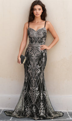 A woman wearing the Lace-Up Long Glitter Prom Dress (Chicas CHF3053), a black floor-length gown with shimmering details, stands against a beige wall and holds a small black clutch.