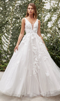 A woman wearing the French White Long Wedding Gown: Ladivine A1028W stands outdoors in front of a green ivy-covered wall.