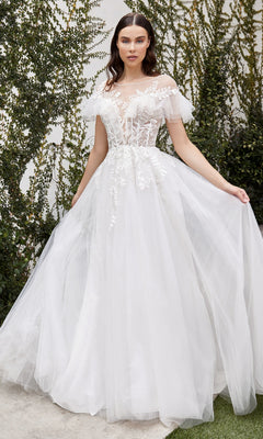 A woman stands outdoors near lush greenery wearing the Ladivine White A-Line Wedding Dress A1070W, featuring off-the-shoulder ruffled floral lace details.