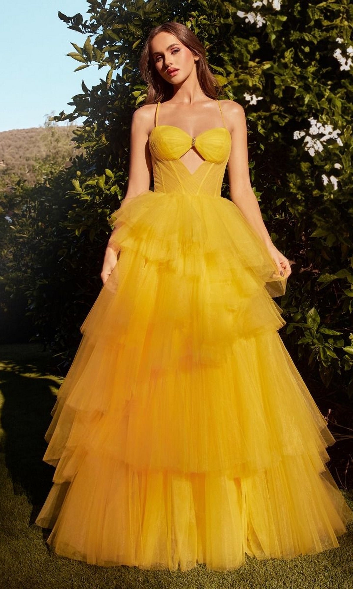 A woman stands outdoors in greenery, wearing the Bright Cut-Out Long Tiered Prom Ball Gown A1238—a vibrant strapless dress with a fitted bodice and flowing tiered skirt.