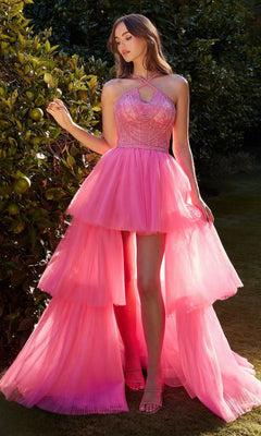 A woman stands outdoors in the High-Low Beaded-Bodice Ruffle Prom Ball Gown A1239, featuring a bright pink color, fitted beaded bodice, and pleated high-low layers, surrounded by green foliage.