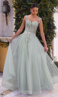 A woman in the Long Pastel A-Line Prom Dress (Andrea & Leo 1258), featuring light green embroidered tulle, stands outdoors by greenery, gracefully holding her skirt.