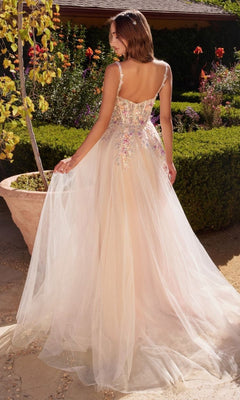A woman stands outdoors in the Floral-Bodice Off White Long Prom Ball Gown A1288, featuring floral embellishments, a tulle skirt, and backless design, holding part of the dress in one hand.