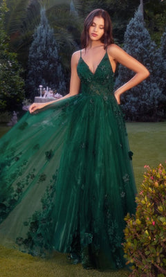 A woman in the Andrea and Leo A1326 Long Glitter Prom Ball Gown stands on a lawn, holding out her green, floor-length floral dress. Shrubs and trees can be seen in the background.
