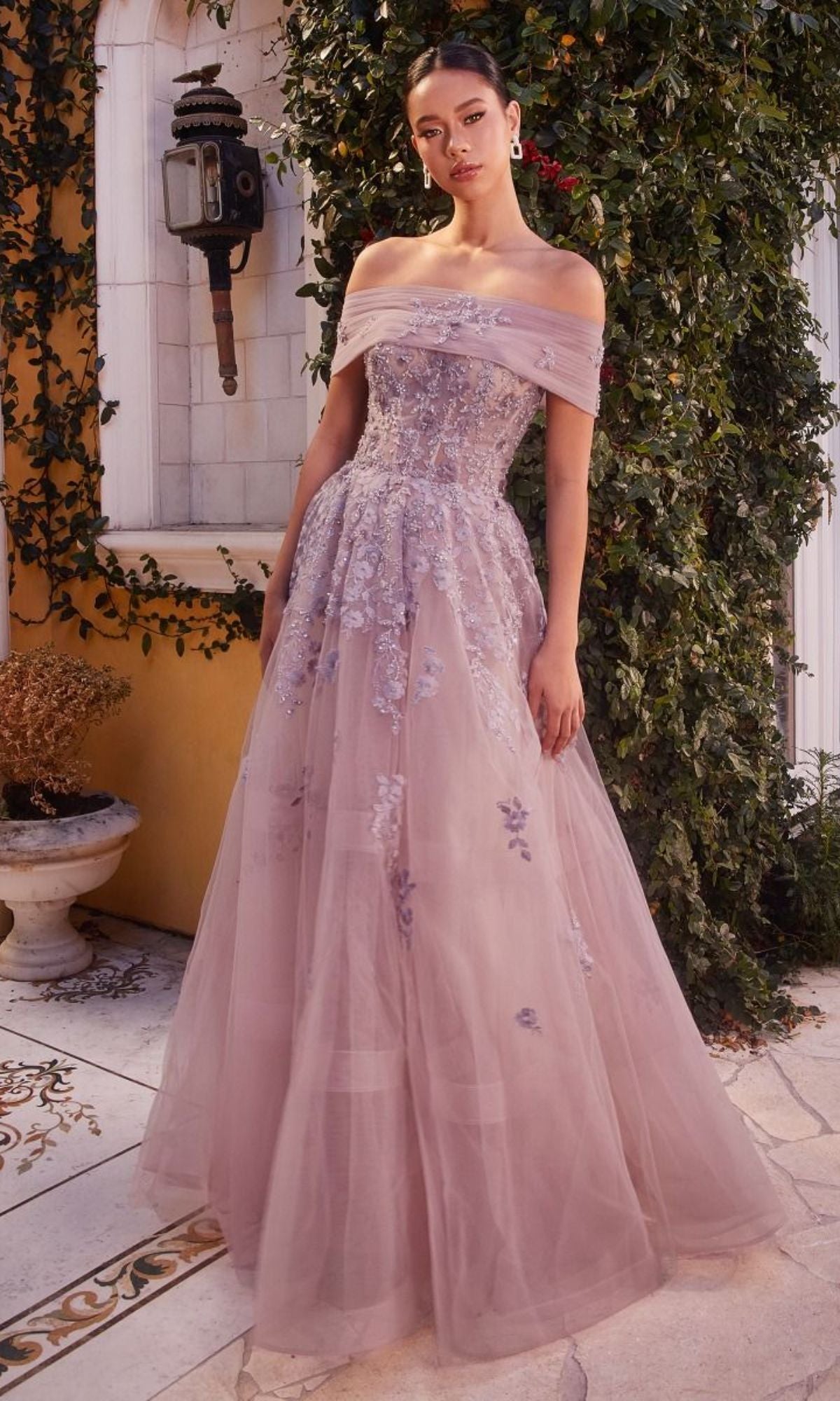 A woman stands outdoors in the Long Strapless Sweetheart A-Line Prom Dress A1348, a lavender floor-length gown with floral embroidery, surrounded by ivy and vintage decor.
