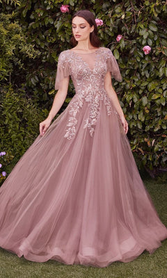 A woman stands outdoors in the Andrea & Leo A1351 short-sleeve prom ball gown, a mauve tulle A-line dress with floral and sequin embroidery and sheer flutter sleeves, posing gracefully amidst leafy greenery.
