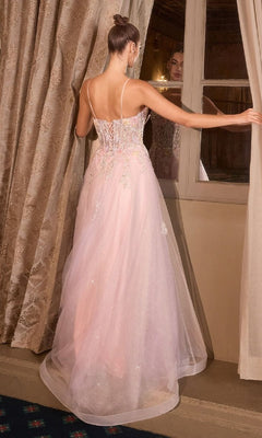 A woman wearing the Classic Long Pink Prom Dress: Andrea and Leo A1477, featuring thin straps and a corset back, stands by a window with her back to the camera, gazing at her reflection.