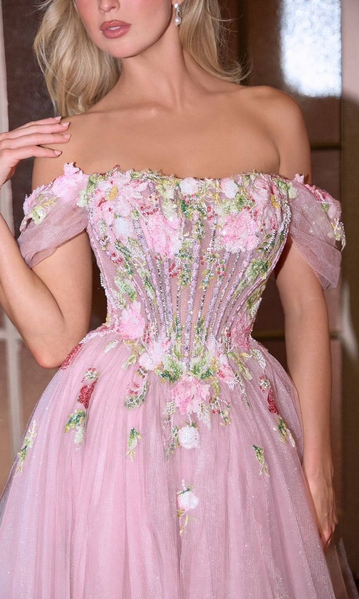 A woman wears the Andrea and Leo A1479 Mauve Pink Prom Ball Gown, an off-the-shoulder dress with floral embroidery, beaded accents, a fitted bodice, and a flowing tulle skirt.