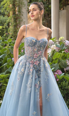 A woman in the Andrea and Leo A1490 long blue prom ball gown stands outdoors by lush greenery and blooming hydrangeas.