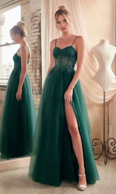 A woman in the Sheer-Waist Long Glitter-Tulle Prom Dress C150, featuring a slit, stands beside a mirror and dress form in a softly lit room.