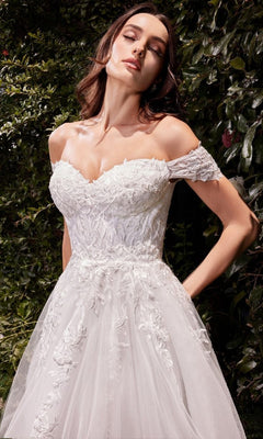 A woman stands outdoors among lush greenery, wearing the Ladivine C159W—an off-white, long wedding dress with off-the-shoulder lace.