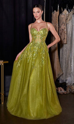 A woman stands in a dressing room with dresses behind her, wearing the Ladivine C177 long prom dress in olive, featuring a sparkly embellished bodice, spaghetti straps, and a full A-line skirt.