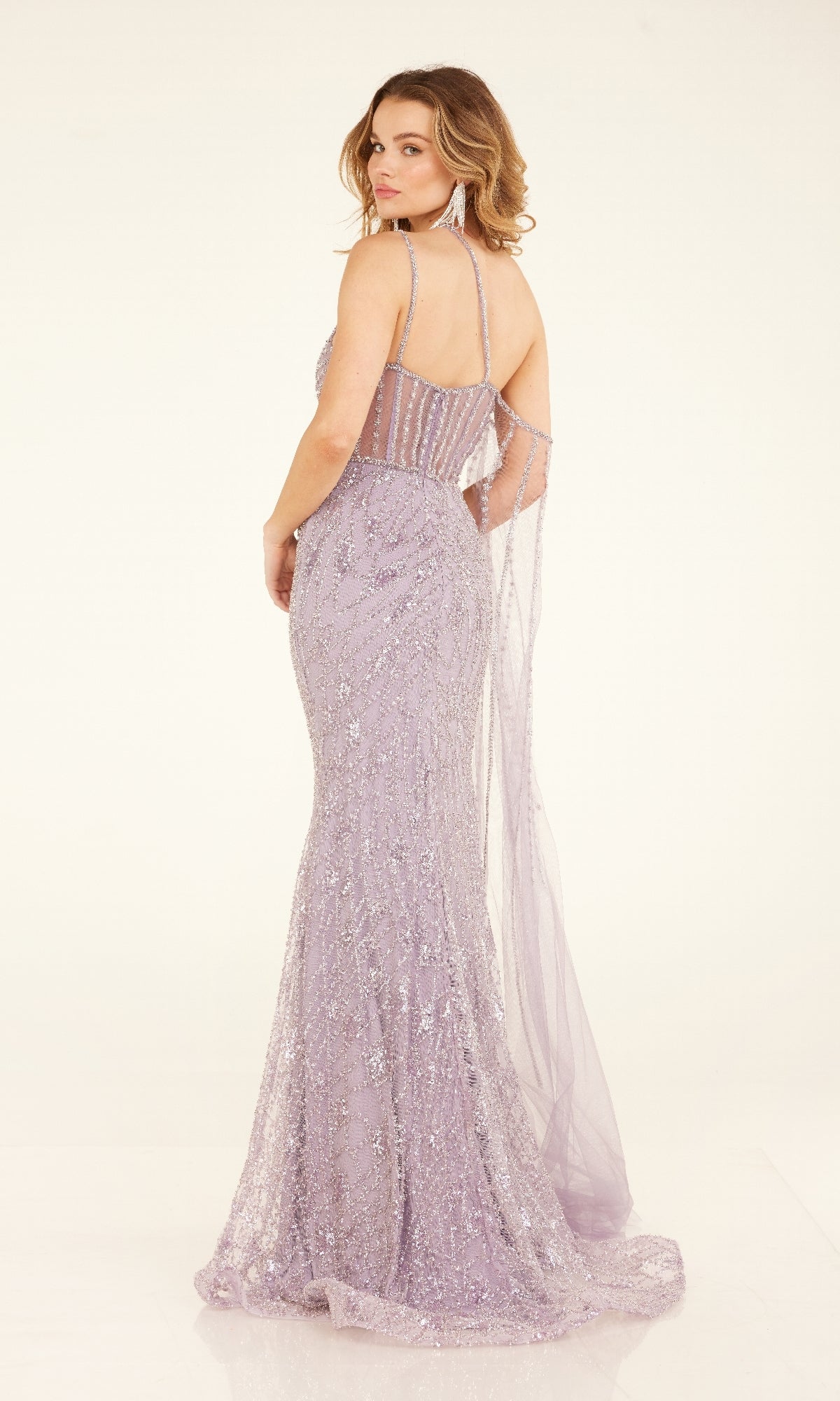 A woman models the Long Formal Dress: Cecilia Couture C280—a floor-length lavender gown with glitter, a one-shoulder neckline, sheer details, and a fitted silhouette—shining against a simple light background.