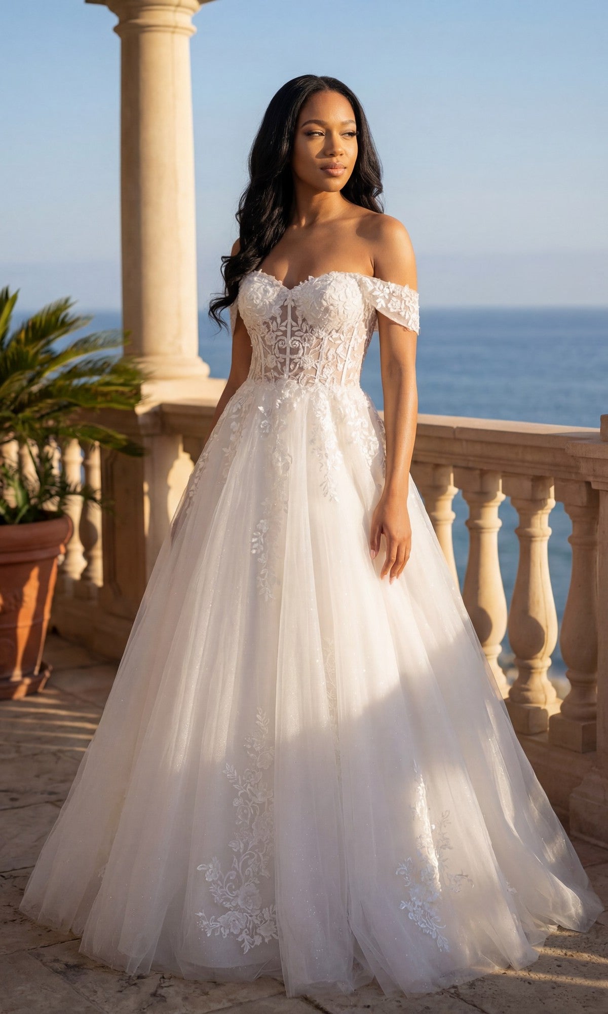 A woman in the Chicas C336 Long Prom Dress in off white, featuring floral lace embroidery and an adjustable lace-up back, stands on a terrace with ocean views and columns behind her.