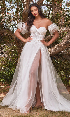 A woman stands outdoors before trees, wearing the Puff-Sleeve Off-White Long Prom Dress CB080W, featuring sheer puff sleeves, a delicately embroidered bodice, and a high slit for an ethereal and elegant look.