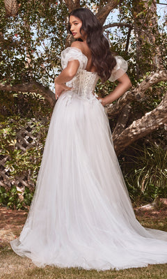 A woman stands outdoors among lush greenery in the Puff-Sleeve Off-White Long Prom Dress CB080W, an off-the-shoulder gown with sheer puff sleeves, a corset back, and a flowing tulle skirt.