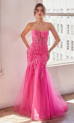 A woman stands indoors by a window wearing the Strapless Sweetheart Long Mermaid Prom Dress CB139 in bright pink, with lace and mesh details, and her hands on her hips.