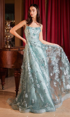 A woman stands indoors beside a wooden piano and red curtains, wearing the Ladivine Long Formal Dress CB144—a floor-length light blue gown with floral lace details and subtle glitter embellishments.