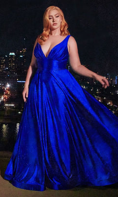 A woman stands outdoors at night in the Ladivine CC2349C Plus Long Glitter Prom Dress, a sleeveless, floor-length gown with a flowing skirt. City lights and buildings glow behind her.